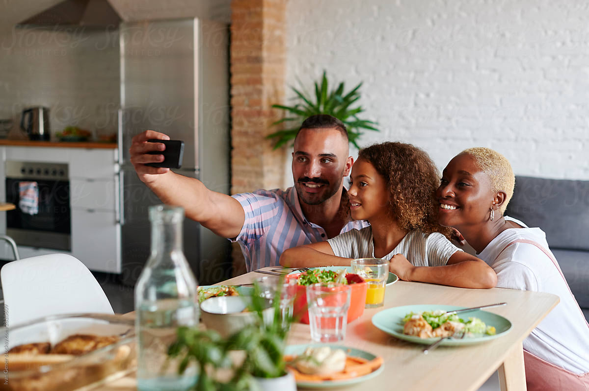Family taking selfies over dinner
