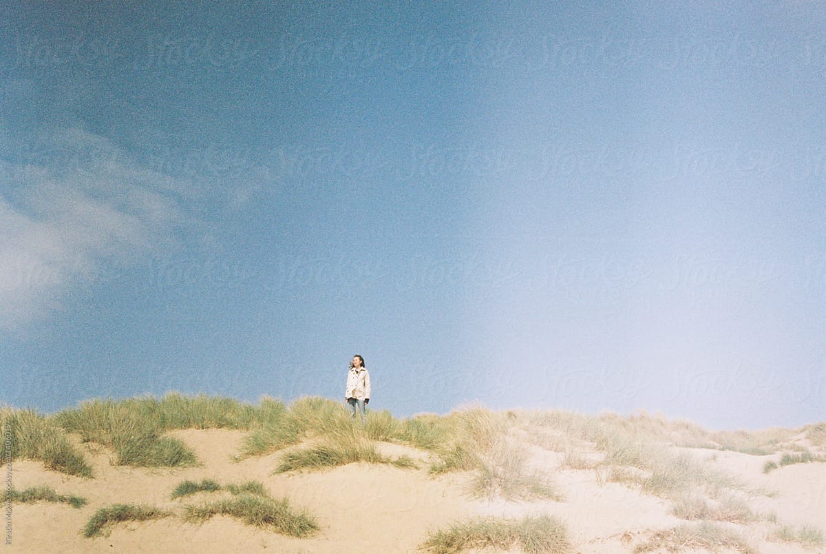 Girl on sand dune with light leak
