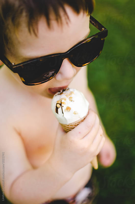 Little boy in sunglasses eating ice cream