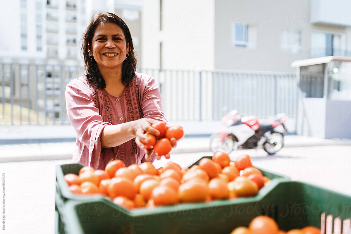 Camera-aware woman holding tomatoes and smiing