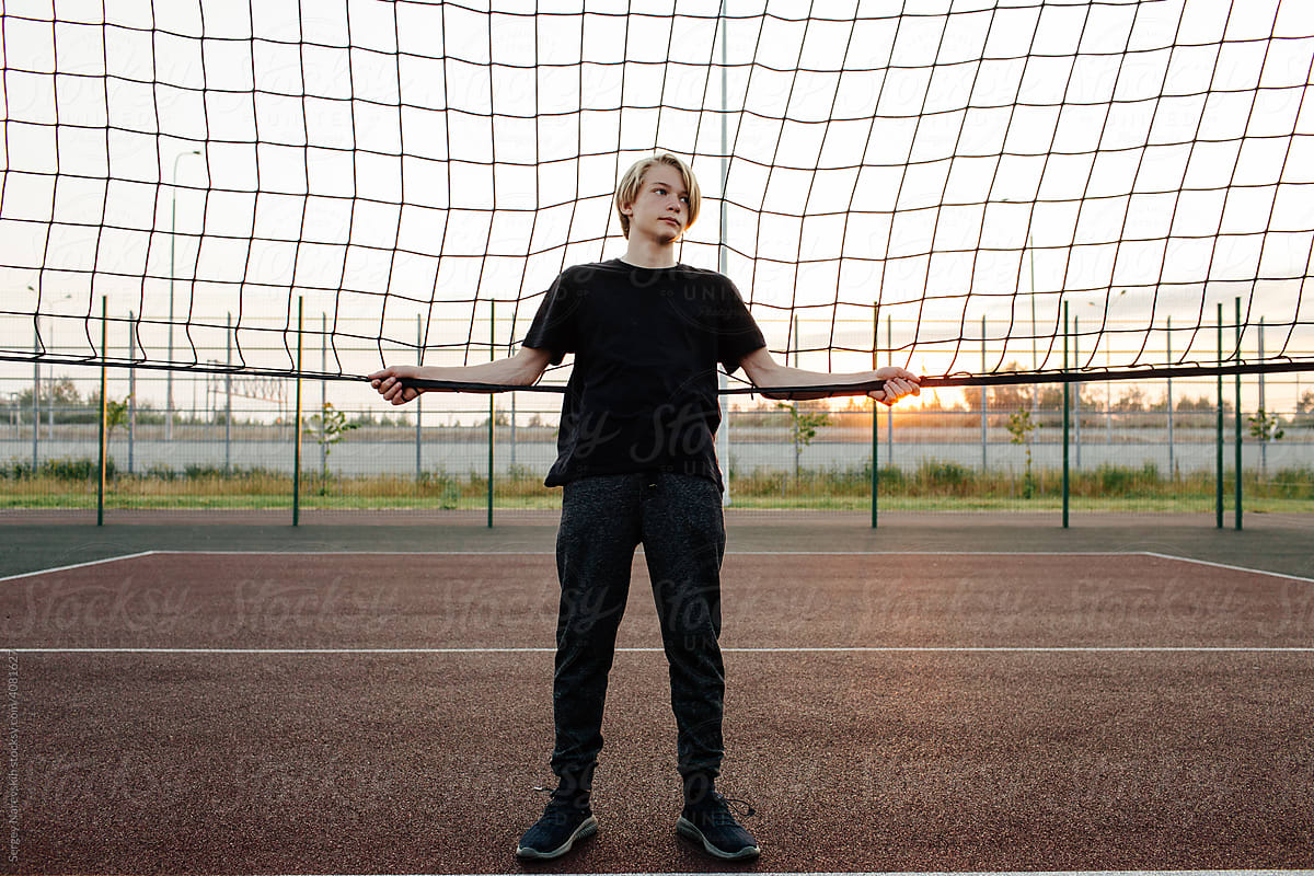 Young man standing near net on sports ground