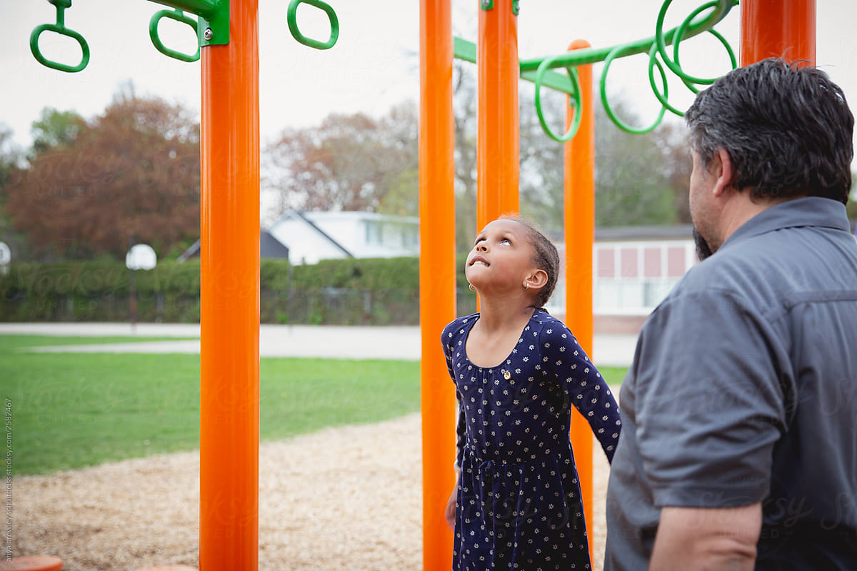 A child looking up at the monkey bars at a playground