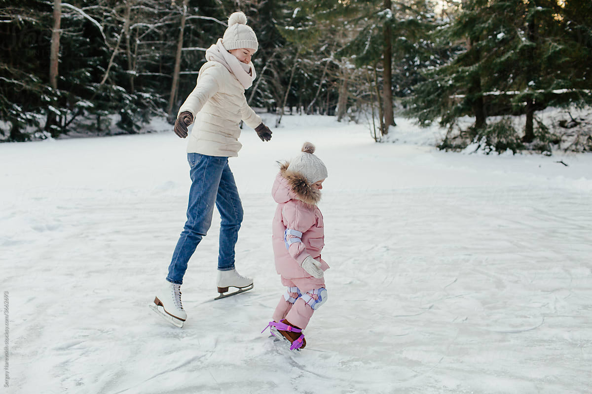 Child with mother spending weekend skating on ice