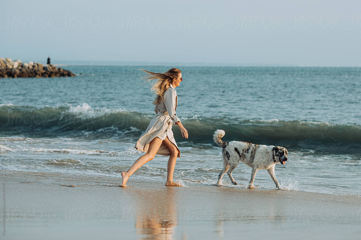 Woman and her dog walking along the beach