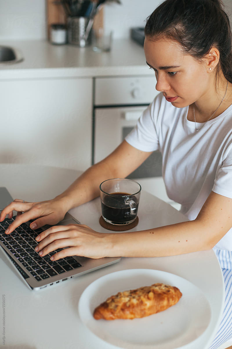 Woman having breakfast and working on a lap top