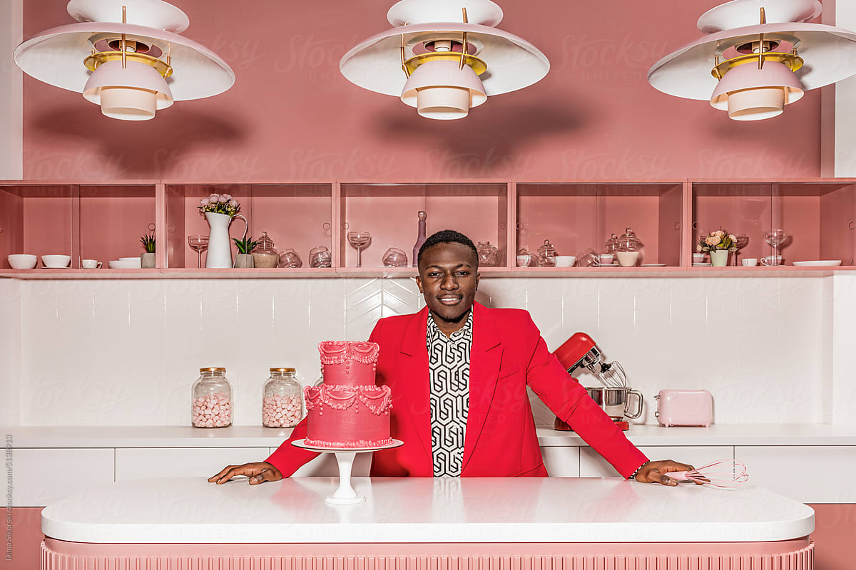 Portrait of a cheerful man in the kitchen with a beautiful pink cake