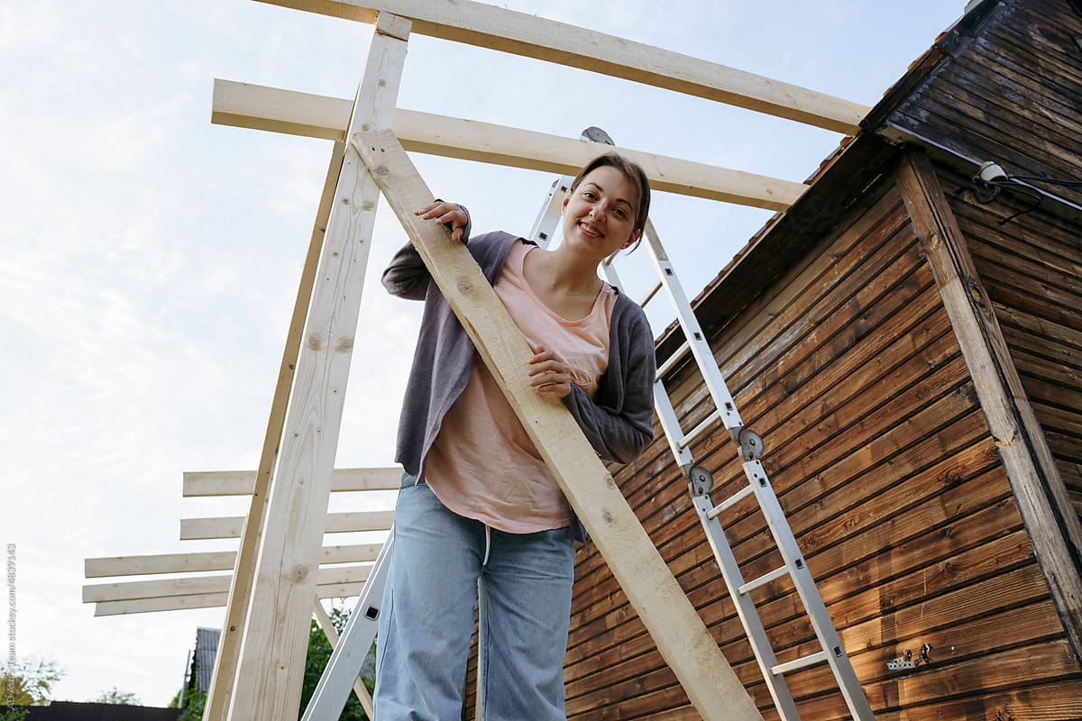 A female carpenter sits on a newly built porch in the backyard