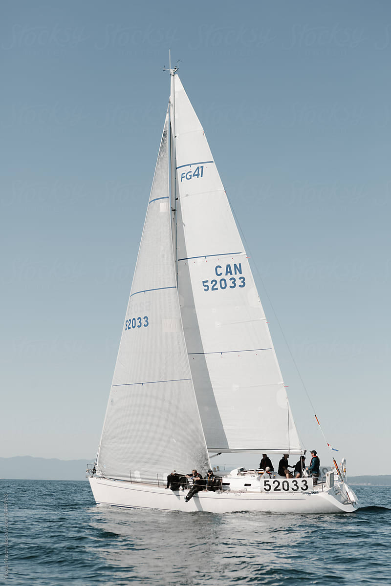 white sailboat at sea in yacht race with crew on board