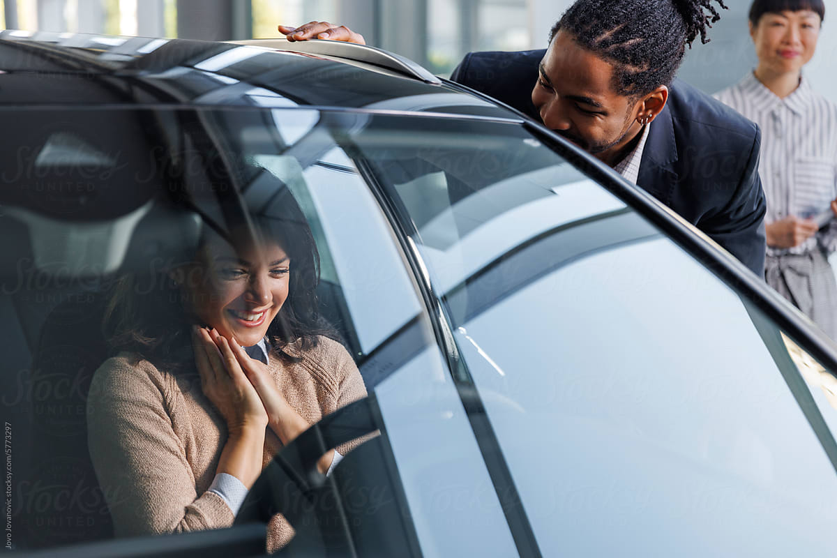 Excited couple examining new car at dealership