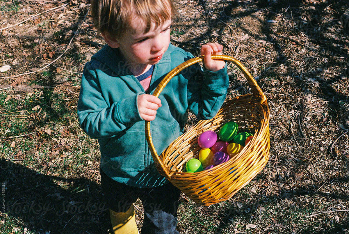 Child Carries Easter Basket Outdoors with Plastic Eggs Inside