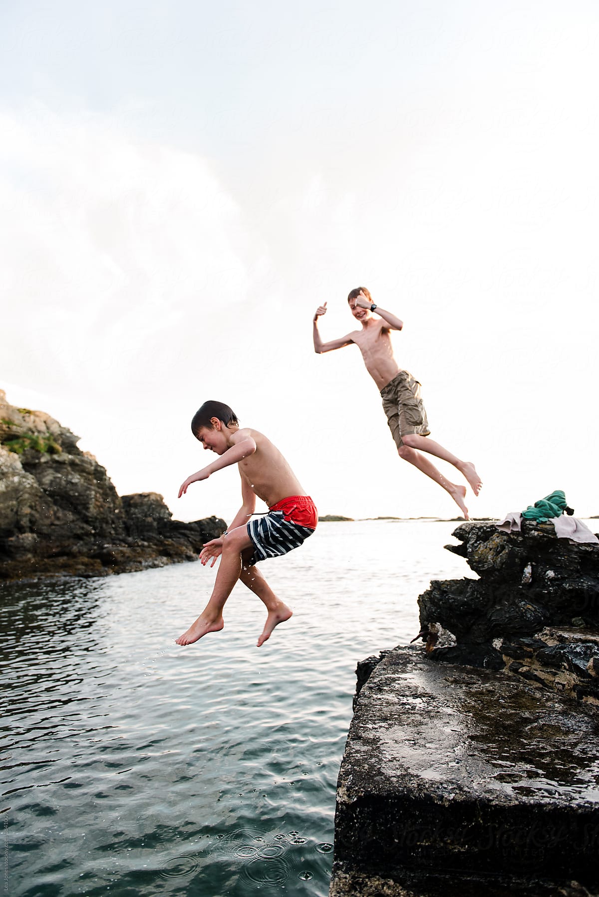 two boys jumping in the ocean