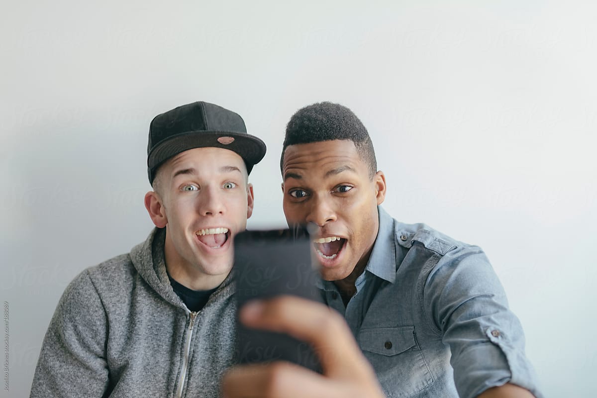 Two Men Friends Having Fun Taking Selfies with Smart Phone Camera App while Making Faces