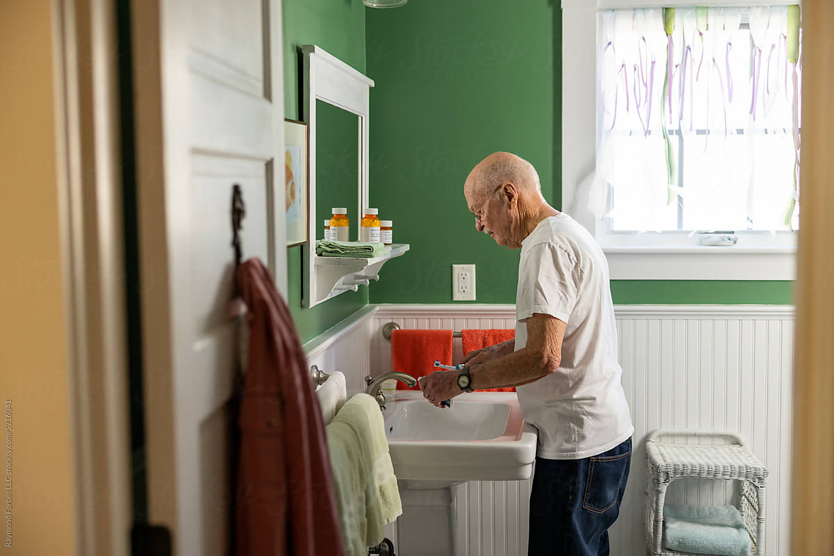 Older man brushing teeth at home