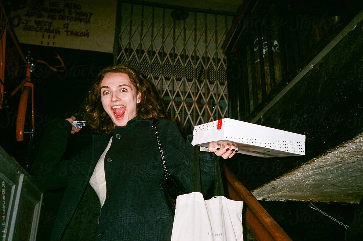 Happy funny girl holding a box off candies in a staircase