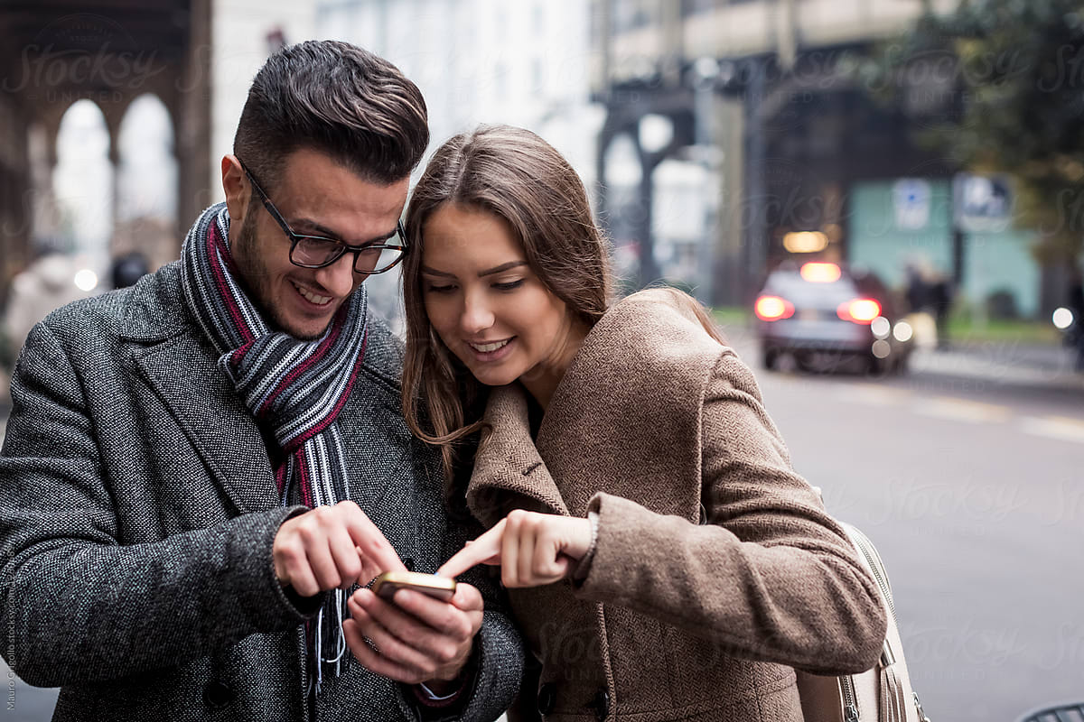 Lovers using a mobile phone in the city in winter