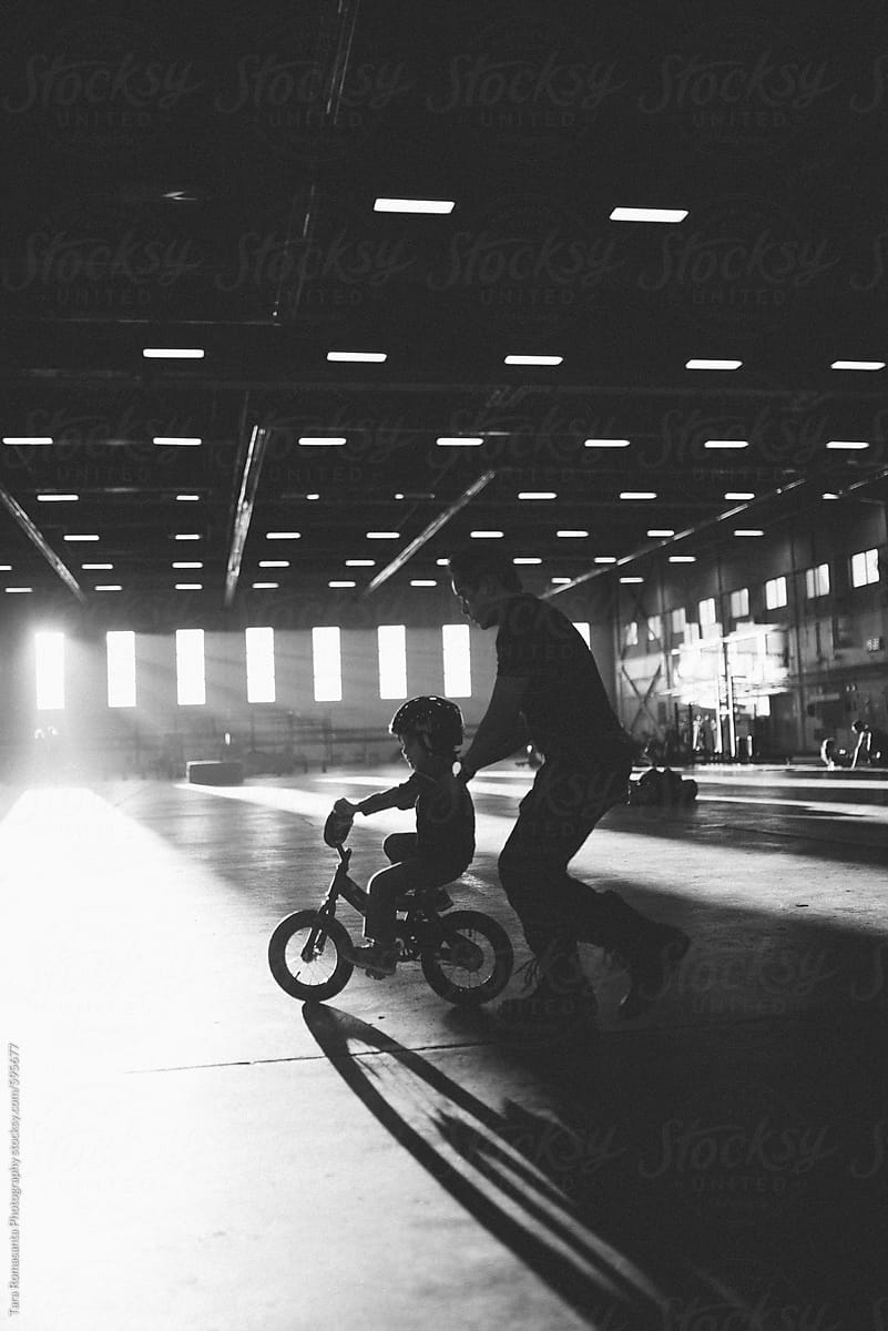 father runs with son learning to ride a bike