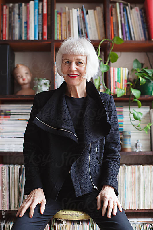 Stylish older woman indoors in front of books and records