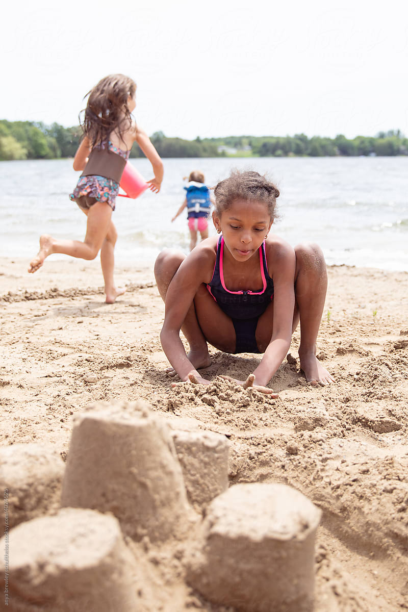 Kids playing on a sandy beach while at a lake