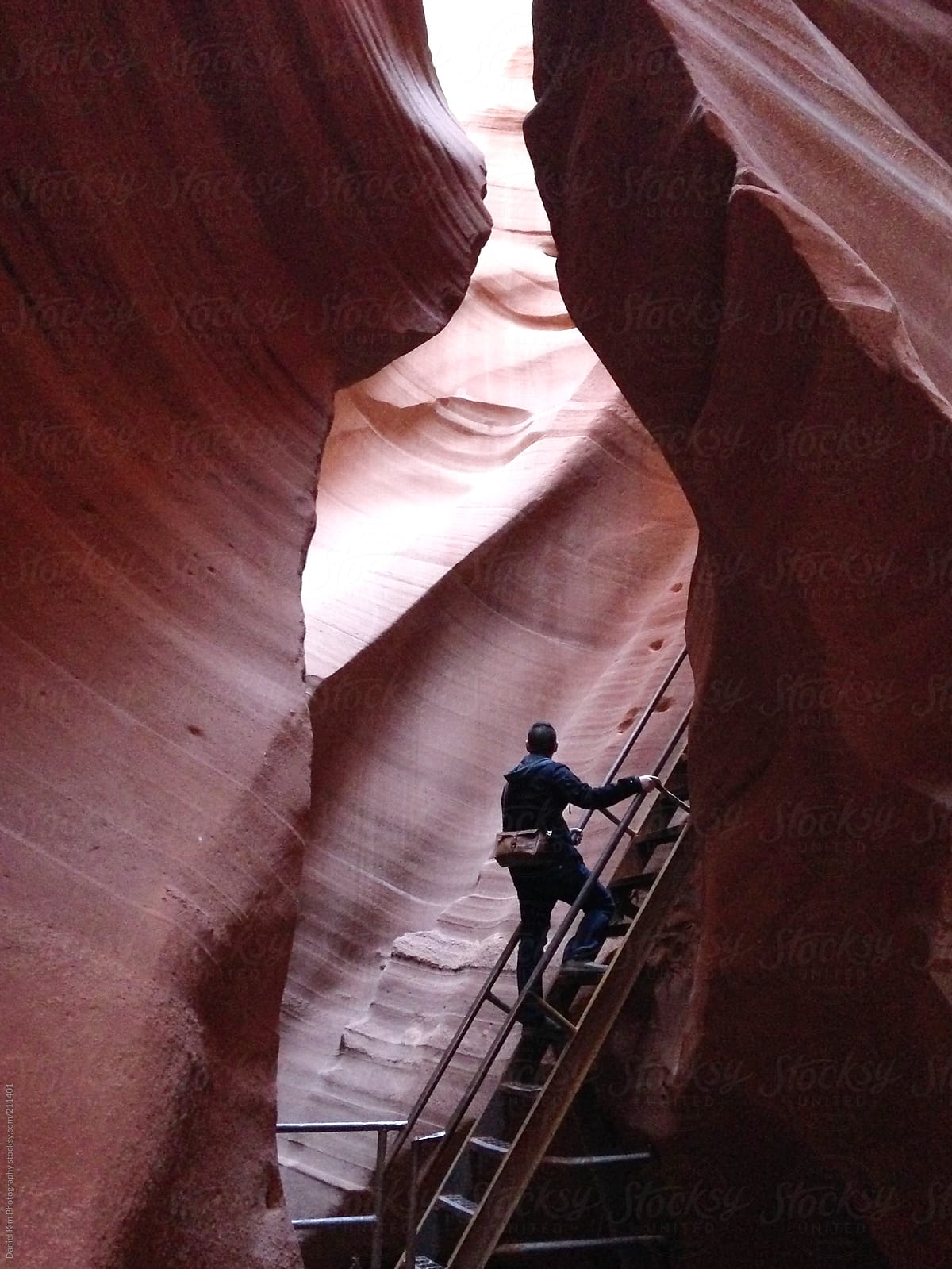man walking up stairs in between canyon walls