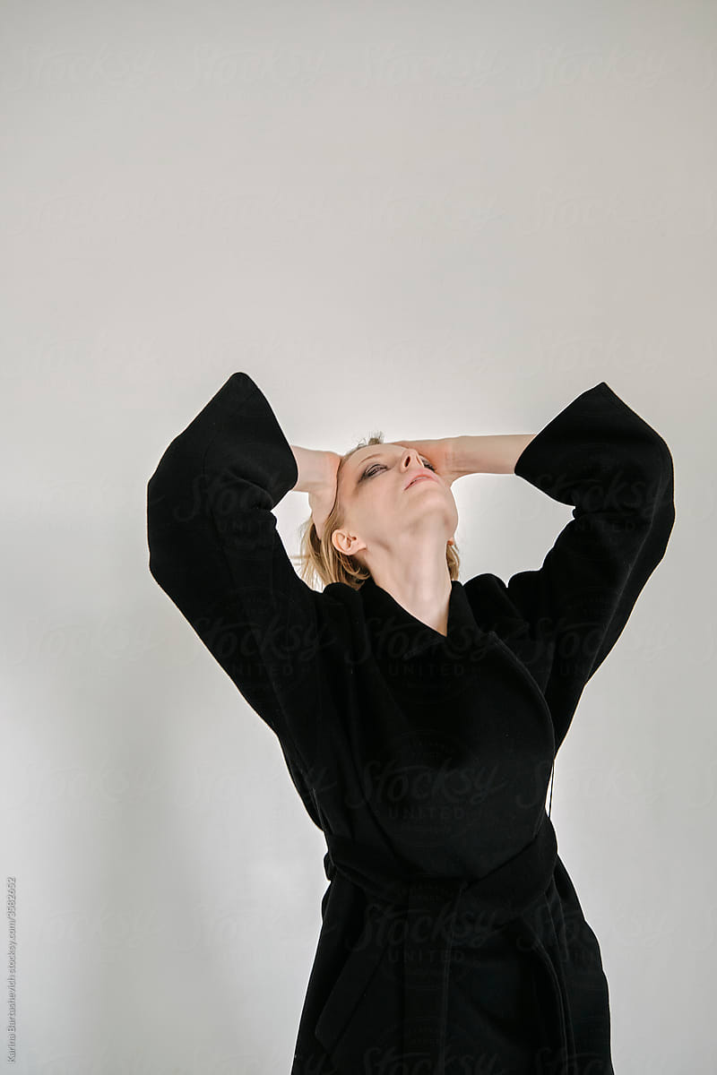 portrait of a beautiful fragile girl in a black coat touching her head back with her hands near her head
