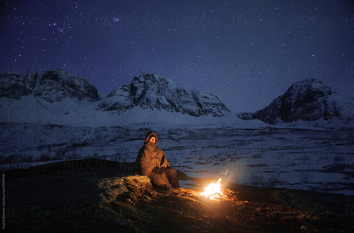 Female hiker sitting around campfire on a cold  winter evening