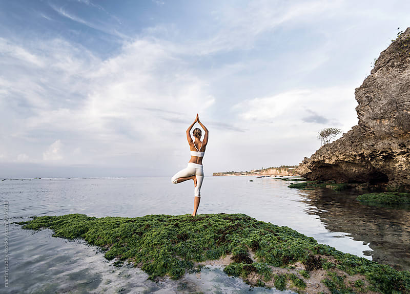 woman practicing yoga at sea shore