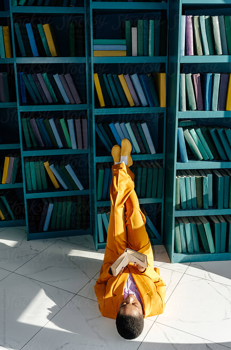 Female in yellow formal suit lying on floor and reading book