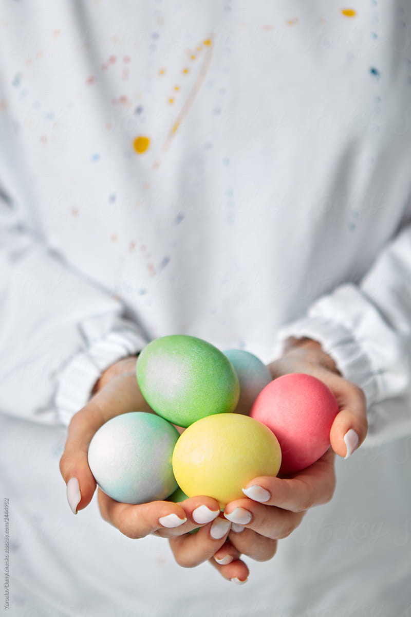 Woman holding in hands a heap of colorful handmade eggs