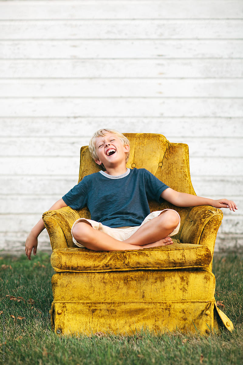 laughing boy sitting in a vintage velvet chair