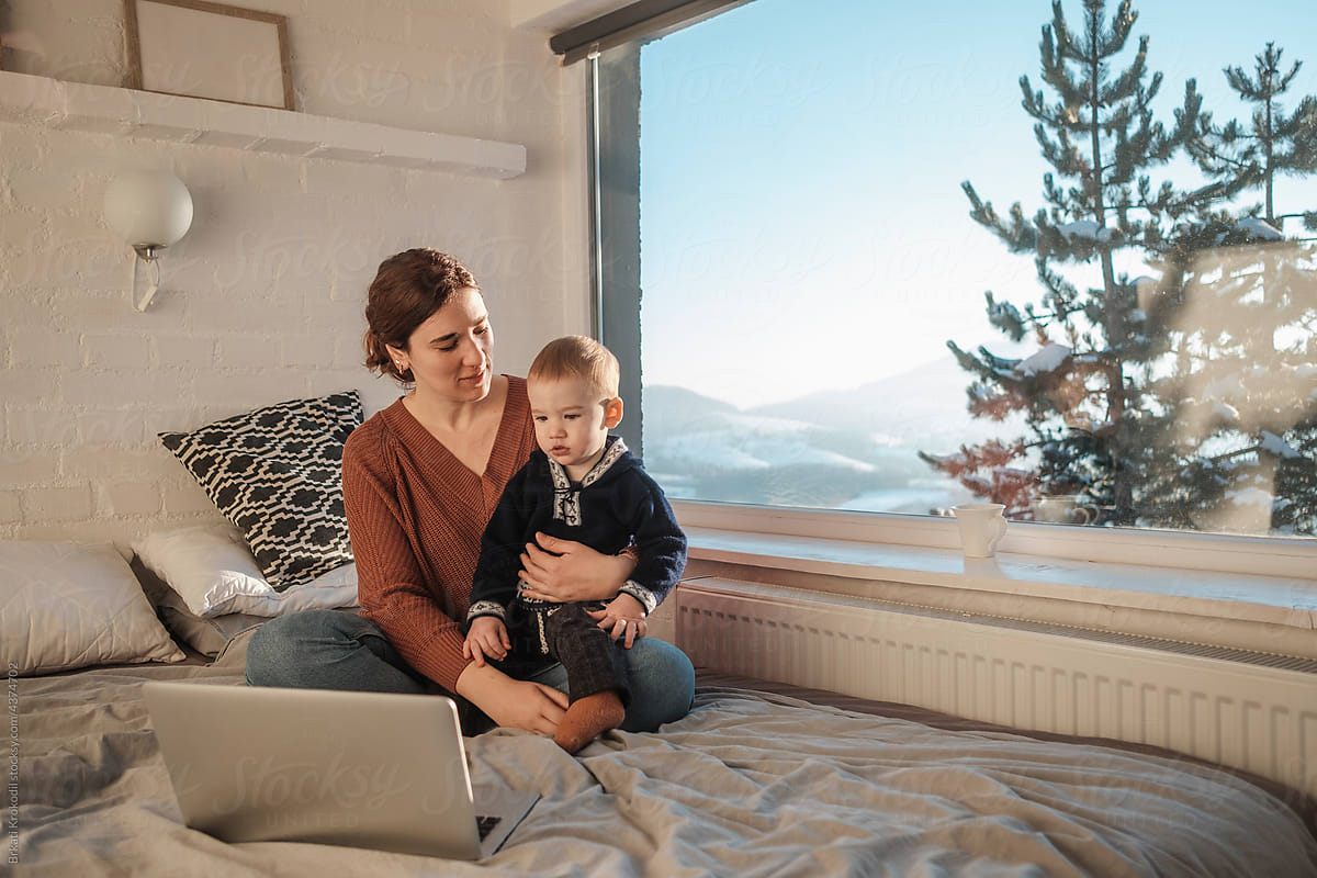 Mother And Son Sitting On The Bed With Laptop