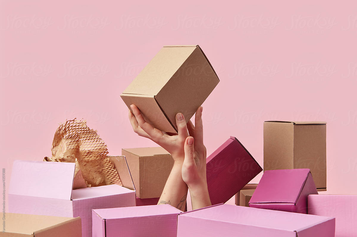 Woman\'s hand in pile with parcels holding brown box