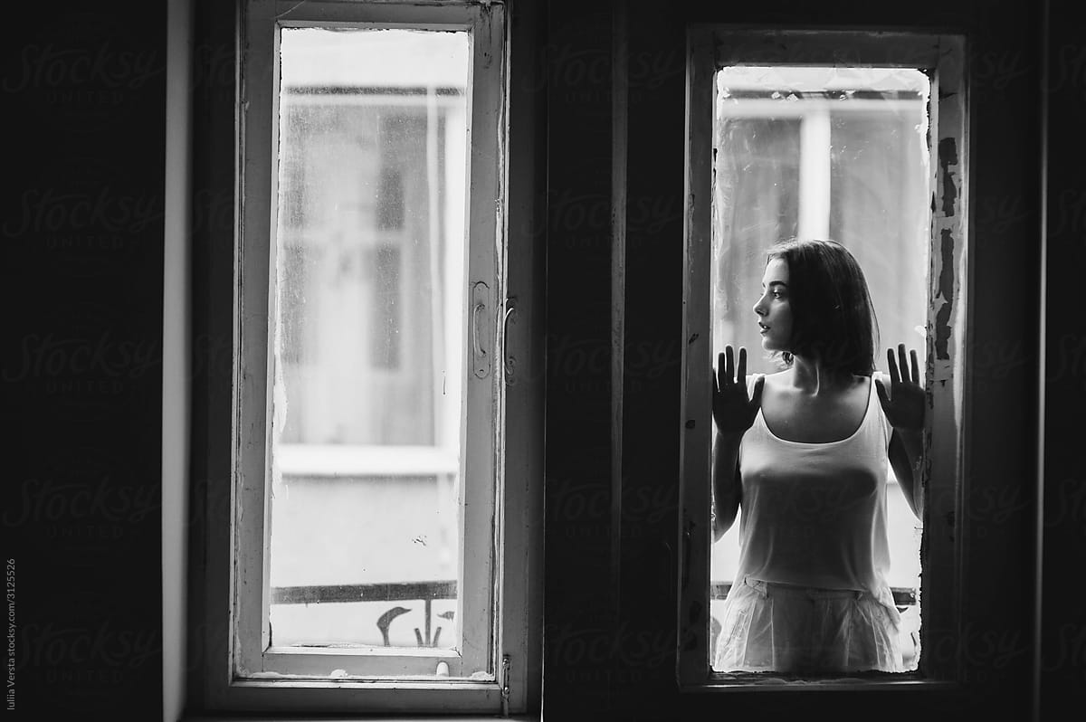 A beautiful girl standing  on the windowsill in the white room