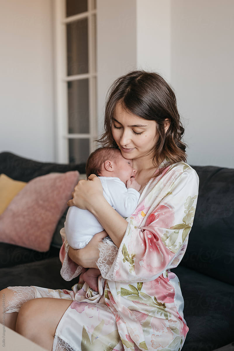 Content mother embracing newborn at home