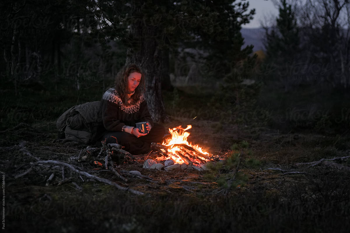Woman sitting by the bonfire in the evening