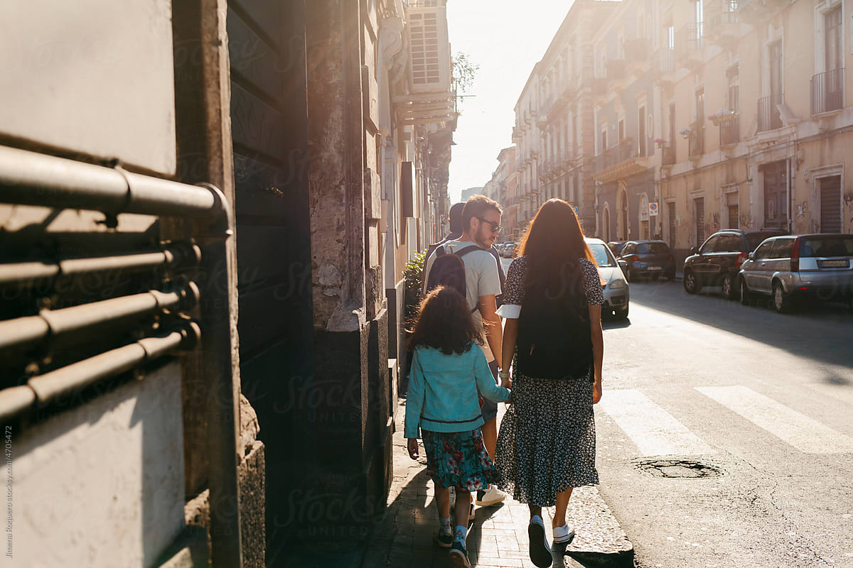 Family walking on old italian city street in sunlight