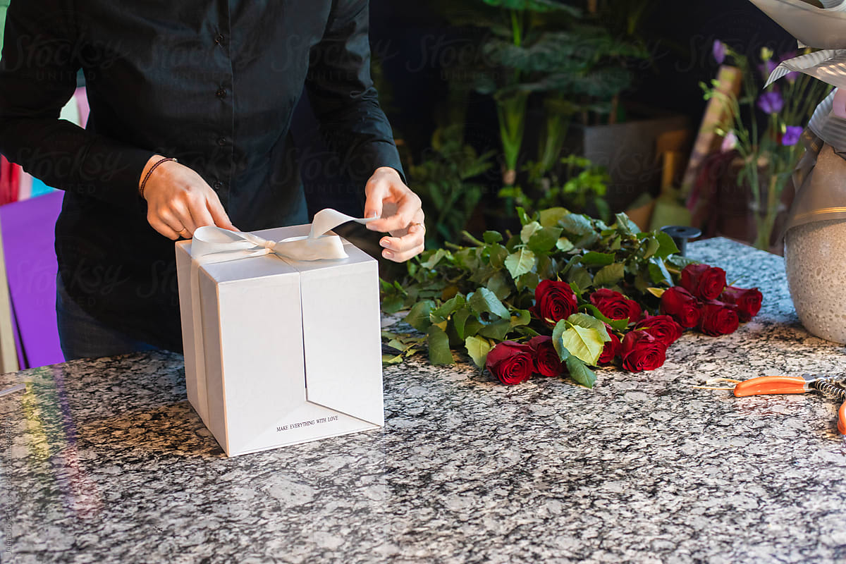 Female florist arranges nine red roses into a special surprise box package