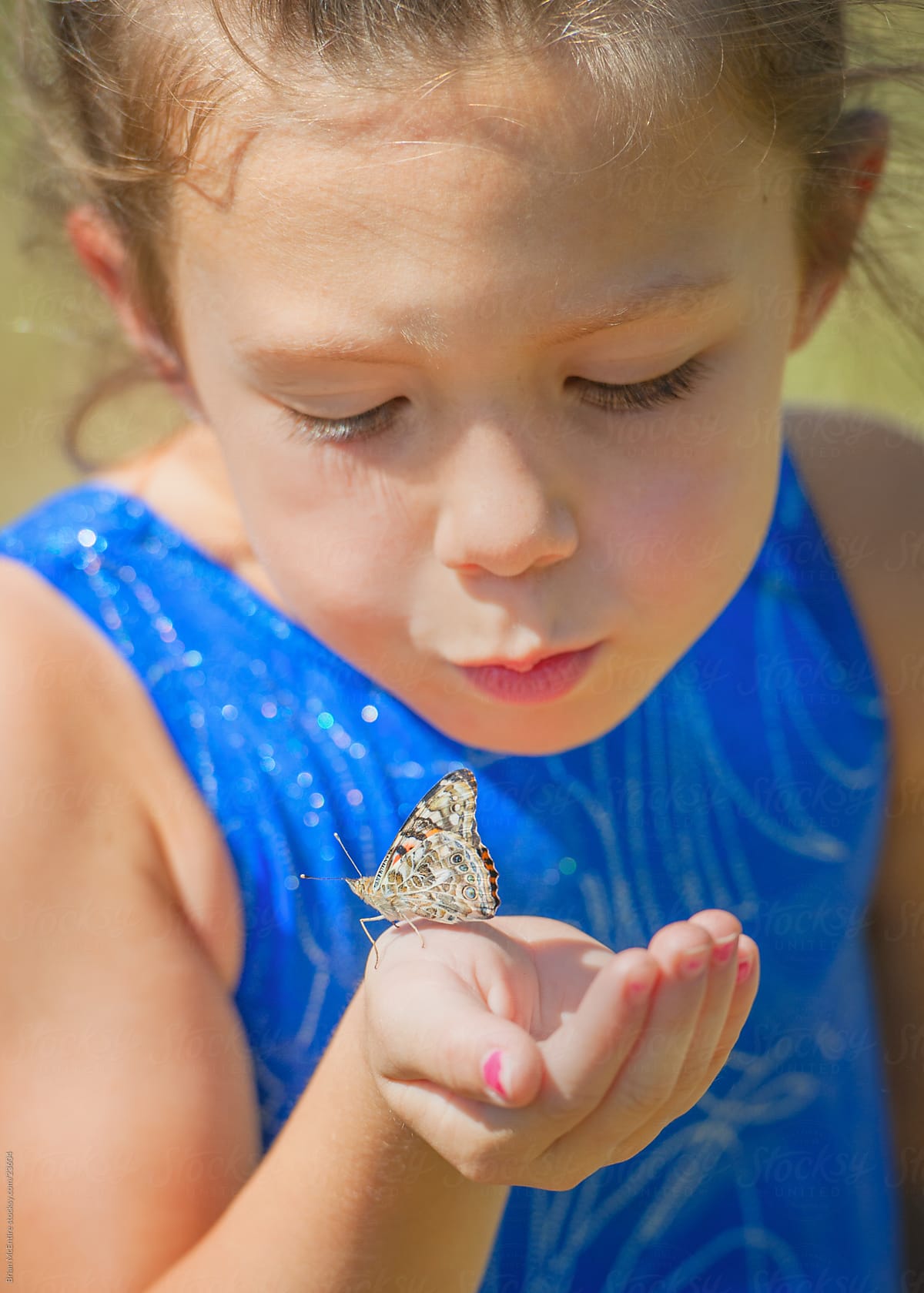Childhood: Young Girl Blows Kiss to Butterfly on Hand
