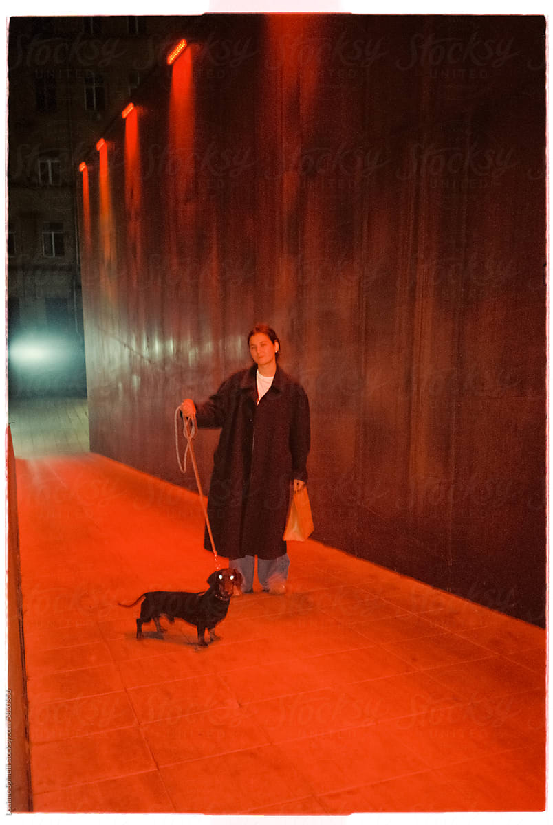 Woman walking her Wiener Dog (Dachshund) next to tall red light wall