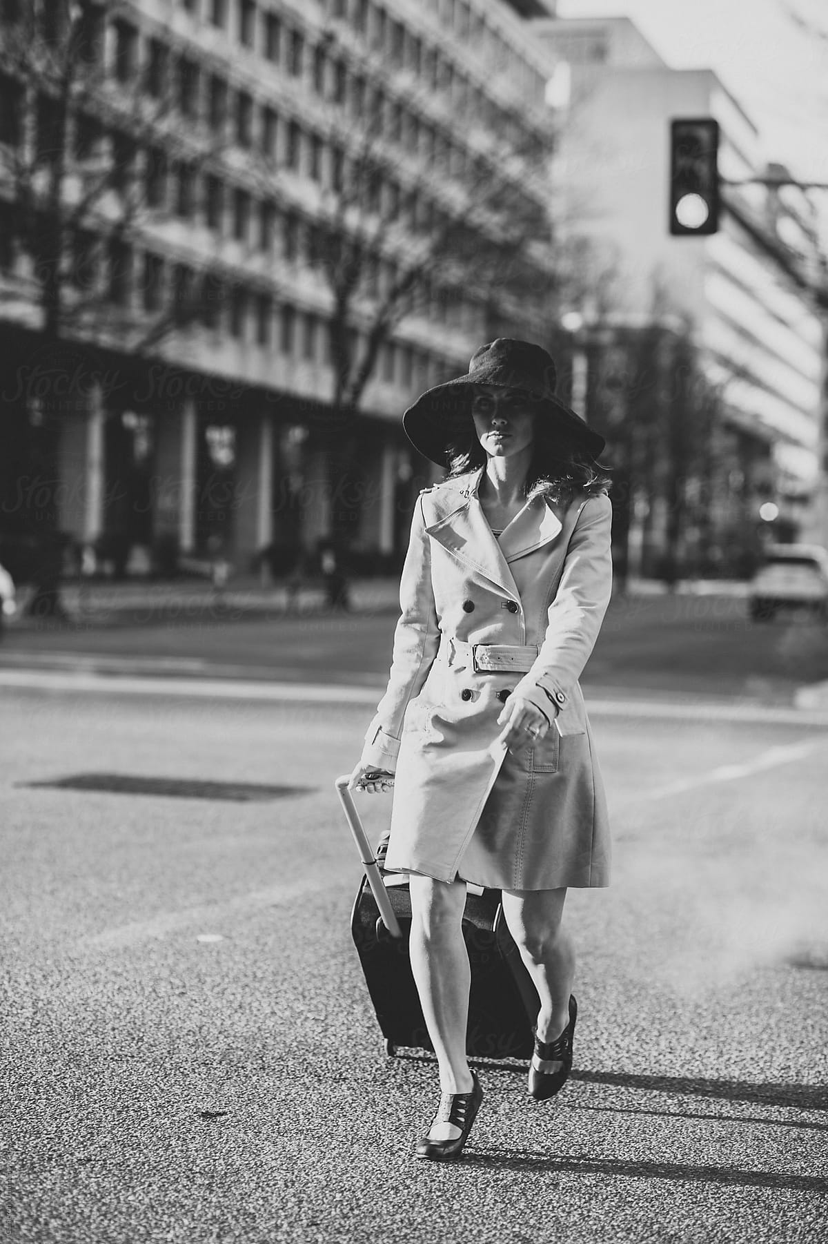 Attractive woman crossing the street with luggage