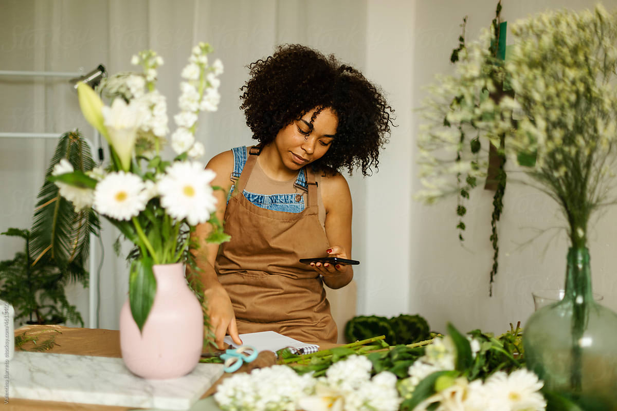 Florist using smartphone in floral studio