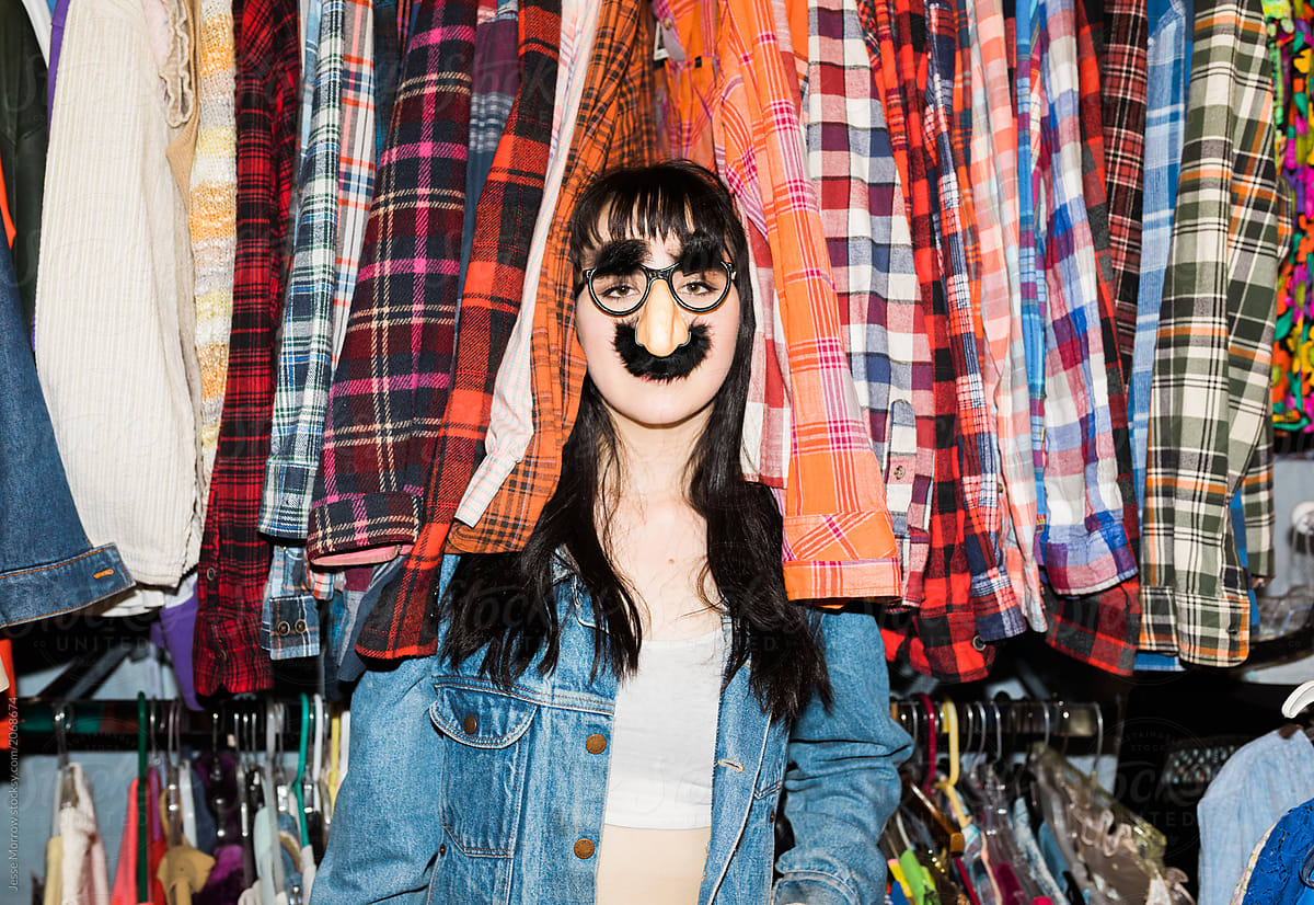 young woman wearing funny mask in clothing rack