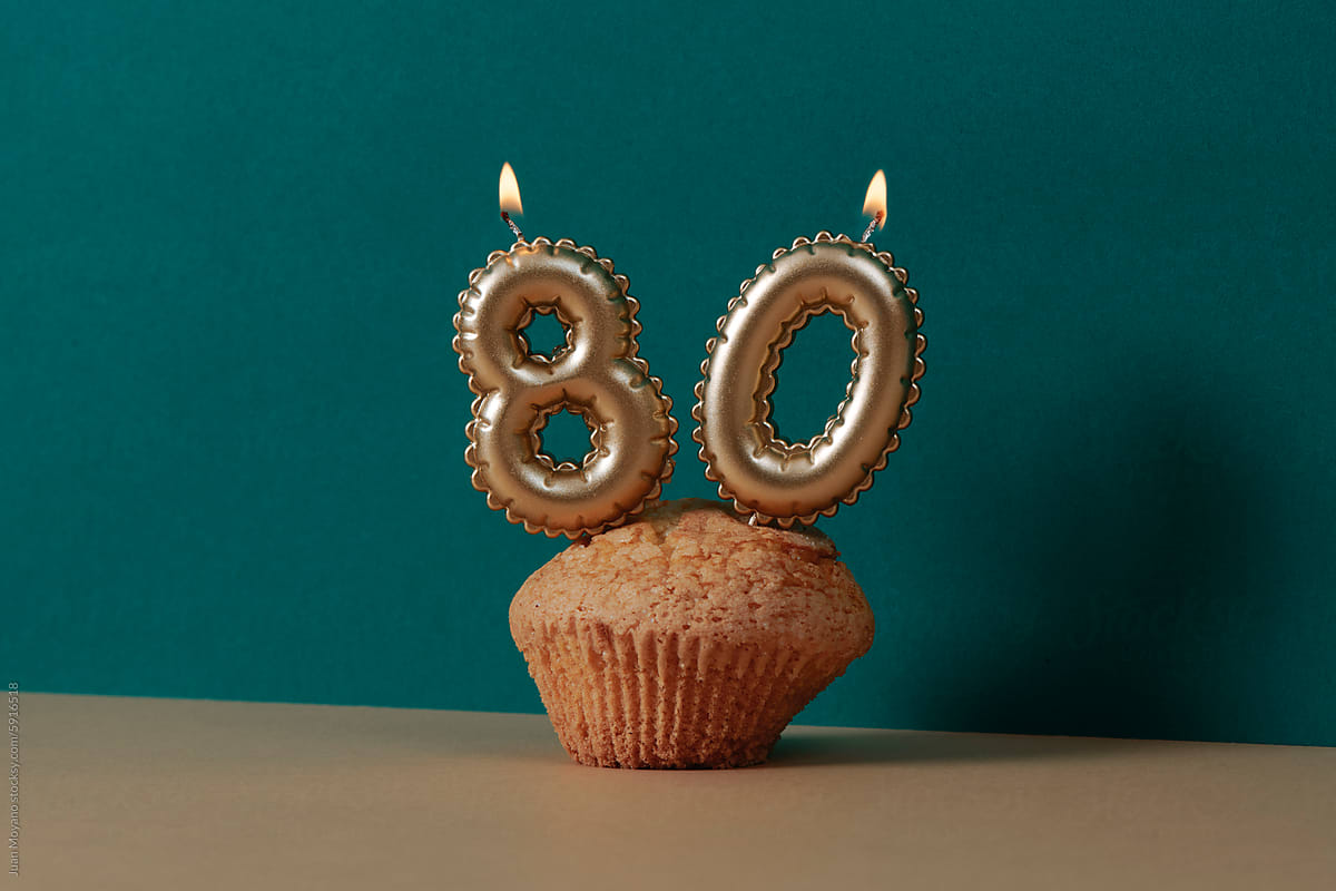 lit candles forming the number 80 on a muffin