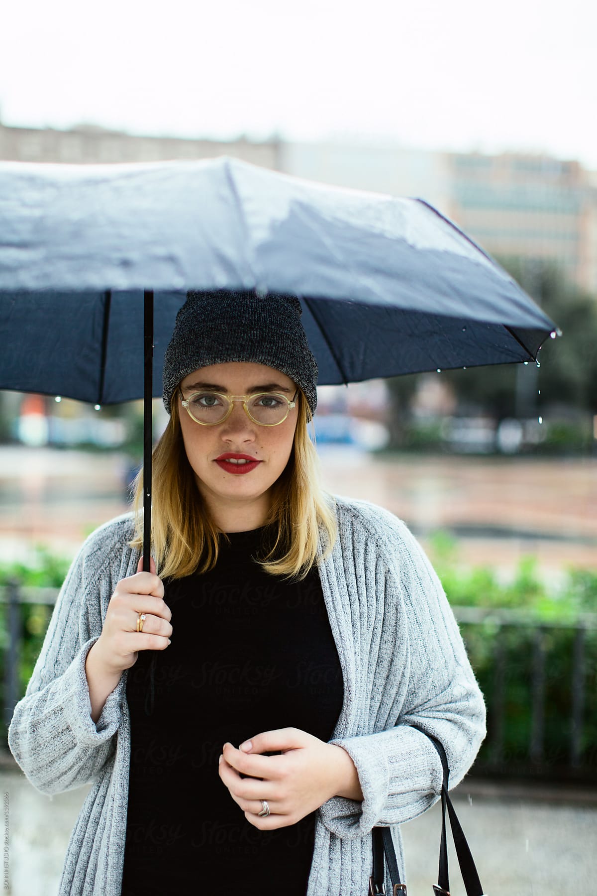 Portrait of a curvy woman holding an umbrella in a rainy day.