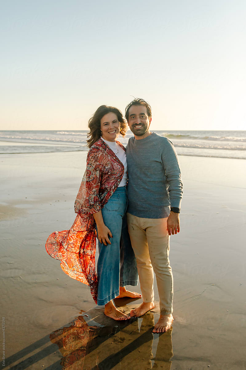 Beautiful barefoot couple on beach at sunset