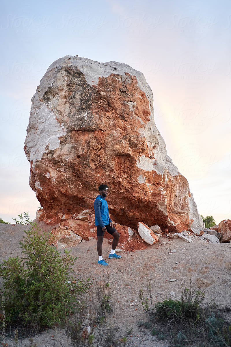 Sportsman standing near rocky boulder