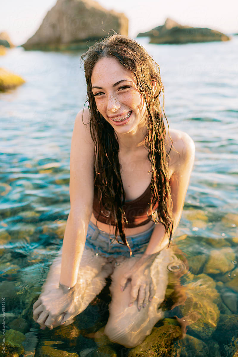Summer portrait of a teenage happy girl with long wet hair at the sea