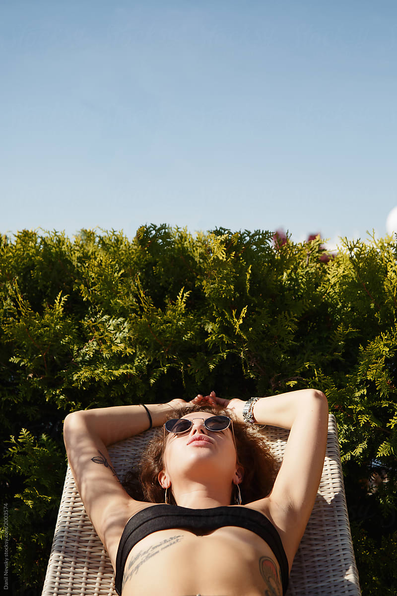 Attractive young woman sunbathing in bikini and sunglasses