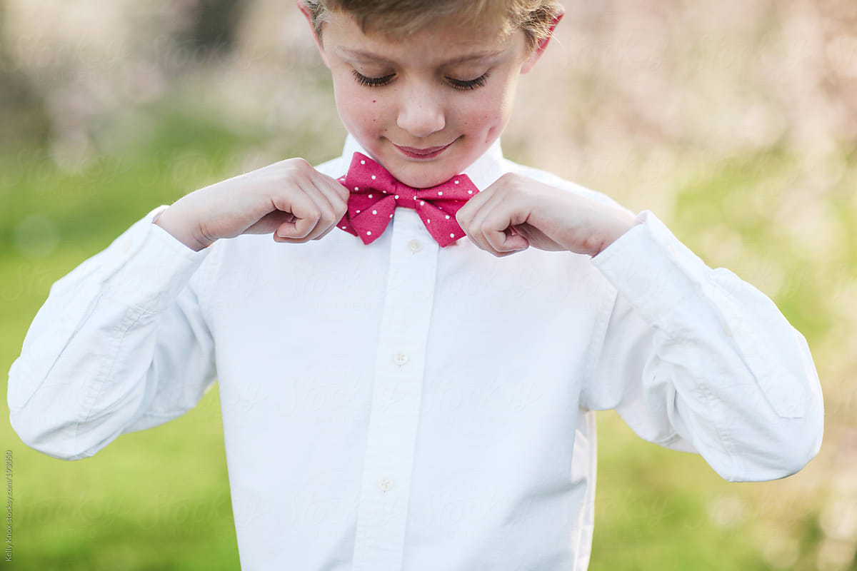 young boy adjusts his bow tie
