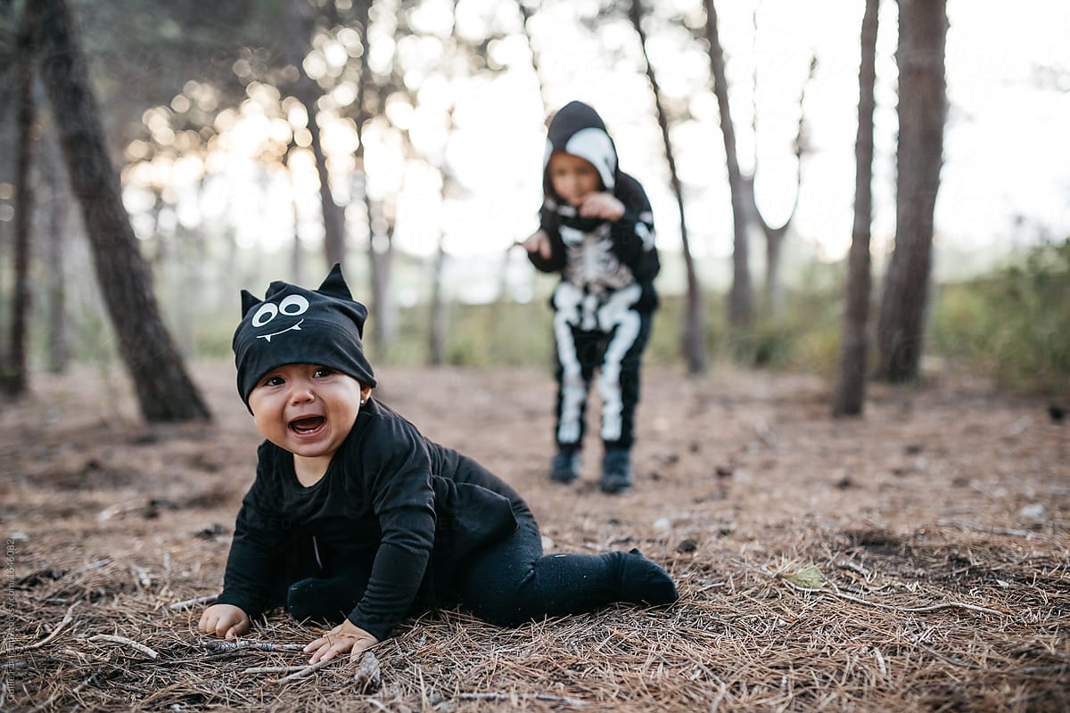 baby in bat halloween costume against skeleton kid