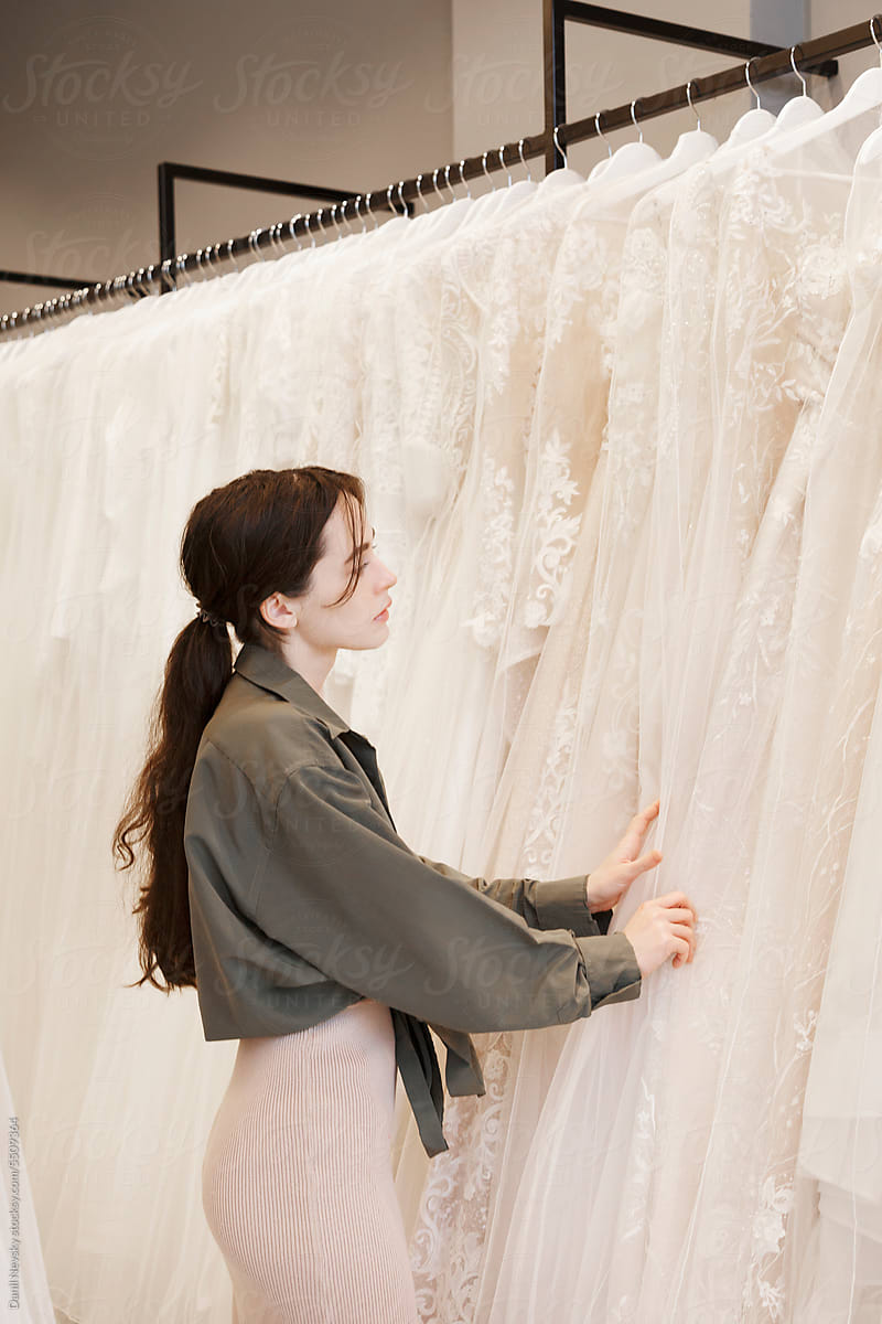 Young woman choosing wedding gown in shop